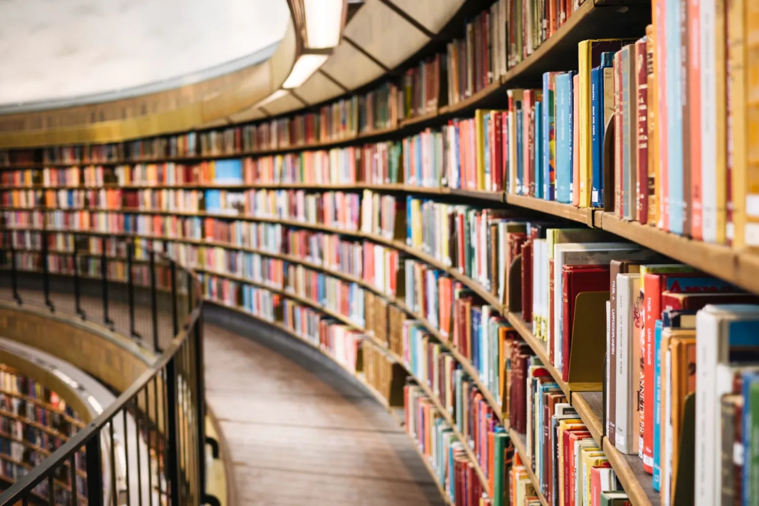The curved balcony stacks of a round library filled with colourful book spines.